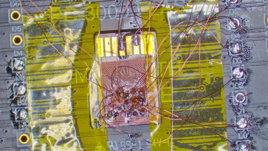 Close-up of board-level micro-soldering under magnification, the technique used to desolder NAND packages for chip-off recovery